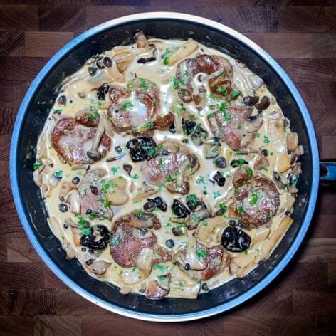 Creamy pork medallions in a rich mushroom and prune sauce, garnished with fresh thyme.