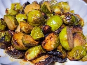 Honey-mustard glazed Brussels sprouts roasted to caramelized perfection, served on a white dish with golden-brown edges and a sticky glaze.