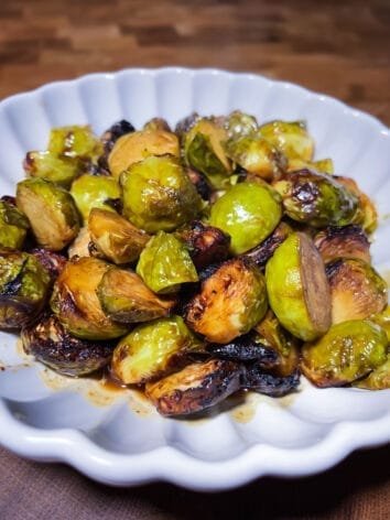 Honey-mustard glazed Brussels sprouts roasted to caramelized perfection, served on a white dish with golden-brown edges and a sticky glaze.
