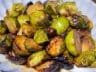 Honey-mustard glazed Brussels sprouts roasted to caramelized perfection, served on a white dish with golden-brown edges and a sticky glaze.