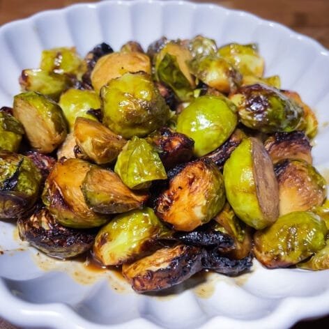 Honey-mustard glazed Brussels sprouts roasted to caramelized perfection, served on a white dish with golden-brown edges and a sticky glaze.