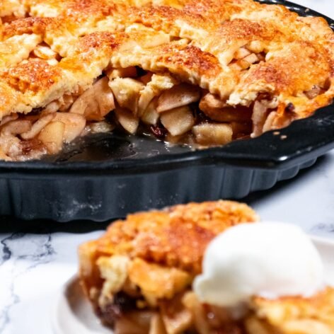 A golden-brown apple pie with a flaky crust, partially sliced to reveal juicy tart apples inside.