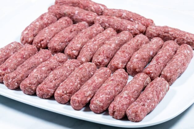 Shaped cevapi rolls arranged on a plate, ready for grilling or frying.