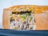 Close-up of a creamy chicken and mushroom pie with a golden crust, showing its rich filling of chicken, mushrooms, corn, and peas.