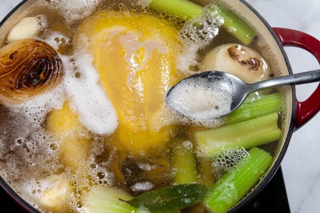 Skimming foam off the surface of simmering chicken stock.