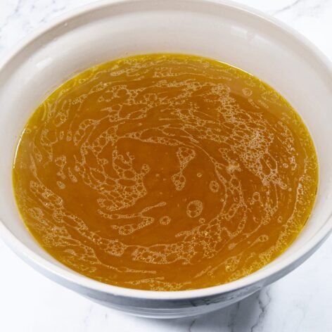 Strained chicken stock in a bowl with golden color.