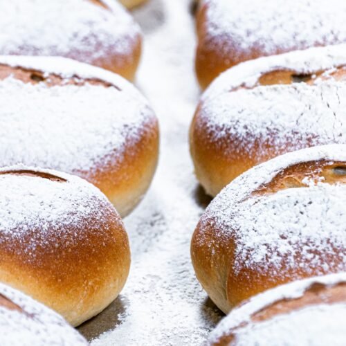 Freshly baked Greek yogurt buns with a golden crust, arranged neatly on a baking sheet.