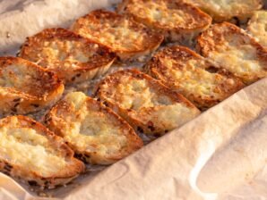 Crispy garlic bread slices with a golden cheesy topping, fresh out of the oven.
