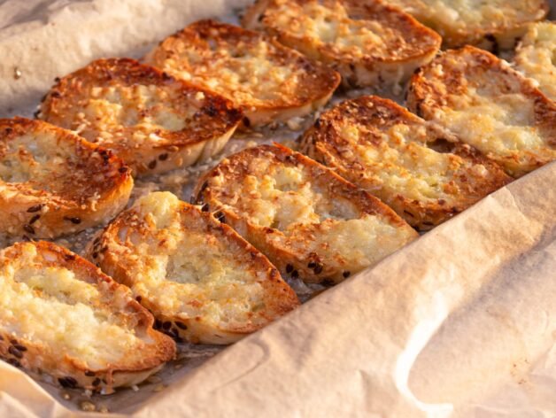 Crispy garlic bread slices with a golden cheesy topping, fresh out of the oven.