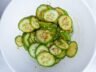 Korean cucumber salad (Oi Muchim) in a white bowl, garnished with sesame seeds and chili flakes.