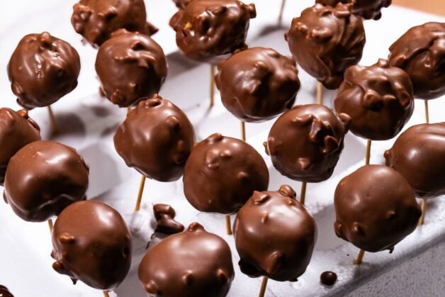 Chocolate-coated Nutella Crunch Bites set on toothpicks in Styrofoam.