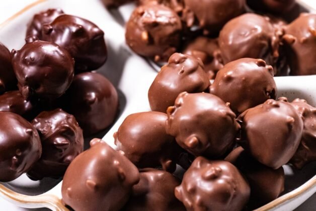 A close-up of glossy chocolate-coated Nutella Crunch Bites in a white dish.