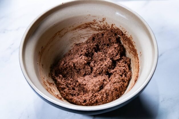 Chocolate and biscuit mixture combined into a thick, textured dough in a bowl.