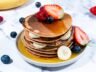 Oatmeal pancakes layered with bananas and garnished with fresh berries on a plate.