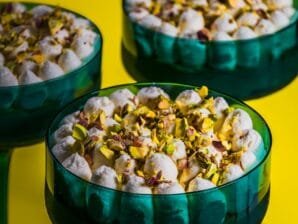Pistachio Delight Dessert Cups with Chocolate Base and Cream Cheese Topping, garnished with chopped pistachios in an elegant emerald-green glass.