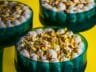 Pistachio Delight Dessert Cups with Chocolate Base and Cream Cheese Topping, garnished with chopped pistachios in an elegant emerald-green glass.