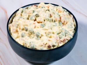 Classic Russian Salad in a dark bowl with creamy mayonnaise dressing.