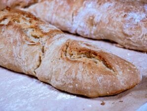 Freshly baked rustic baguettes with a crispy golden crust resting on a parchment-lined baking sheet.
