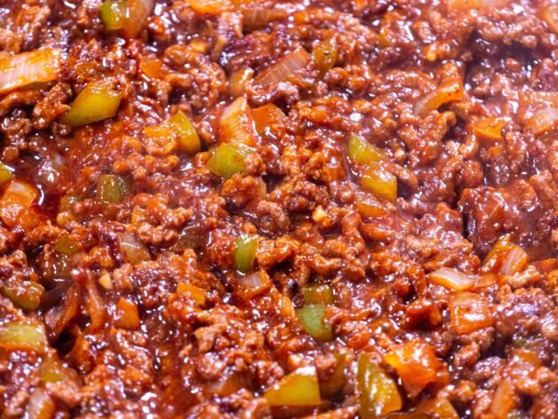 Close-up of Sloppy Joes filling with ground beef, bell peppers, and onions simmering in a rich tomato sauce.