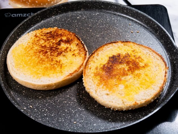 Two golden-toasted sandwich buns in a skillet, ready for Sloppy Joes.