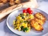 Plate of spinach scrambled eggs served with garlic bread slices and cherry tomatoes.
