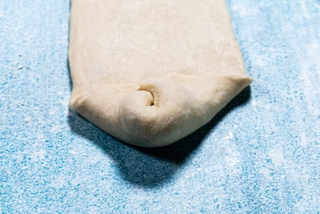 Folding the edges of the dough inward to shape the bun.