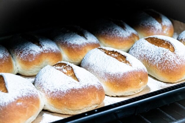 Golden brown buns with a flour-dusted surface baking inside the oven.
