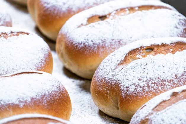 A close-up of freshly baked buns with a golden crust and soft flour dusting.