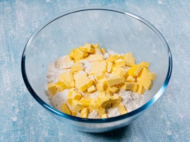 Cubed butter and flour in a glass bowl, ready to be combined for the crust.