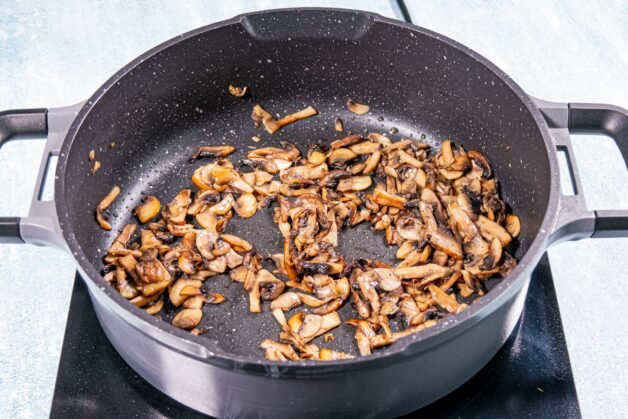 Golden-brown sautéed mushrooms in a black pan.