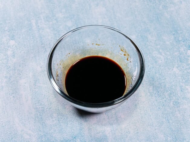 A small glass bowl filled with a dark sauce made of soy sauce, oyster sauce, and sesame oil.