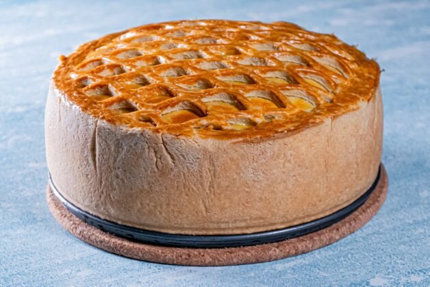Fully baked chicken and mushroom pie with a golden lattice crust on a cork trivet.