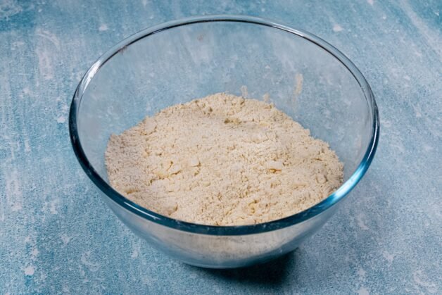 Flour and butter mixture resembling coarse crumbs in a glass bowl.