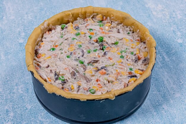 Springform pan filled with creamy chicken and vegetable filling, ready for topping.