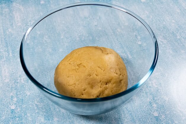 A smooth ball of dough in a glass bowl, ready for chilling.