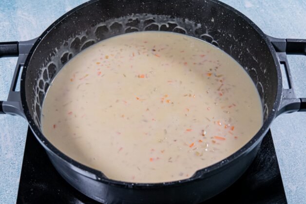 Creamy sauce for chicken and mushroom pie filling simmering in a pan.