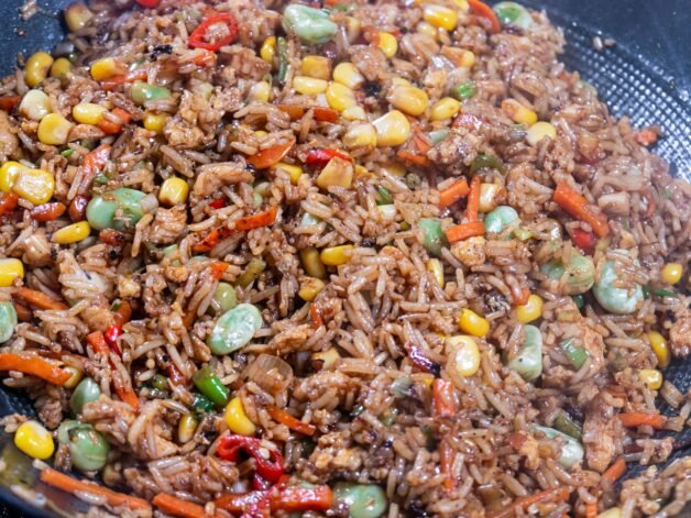 Chicken fried rice coated in a rich, dark sauce with vibrant vegetables.