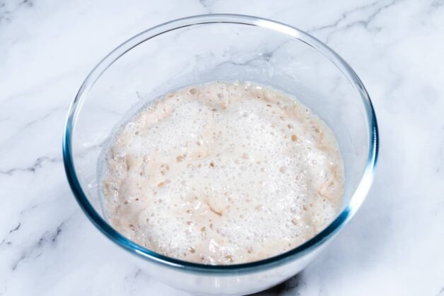 Foamy, activated yeast in a glass bowl, ready for making dough.