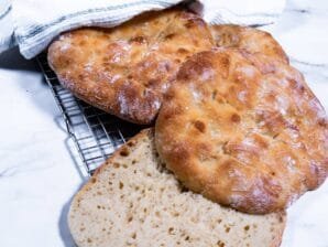 Sliced traditional flatbread revealing a soft, airy crumb on a cooling rack.