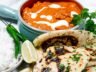 Creamy Butter Chicken in a rich tomato-cashew sauce, served with garlic naan, basmati rice, fresh green chilies, and lime wedges.