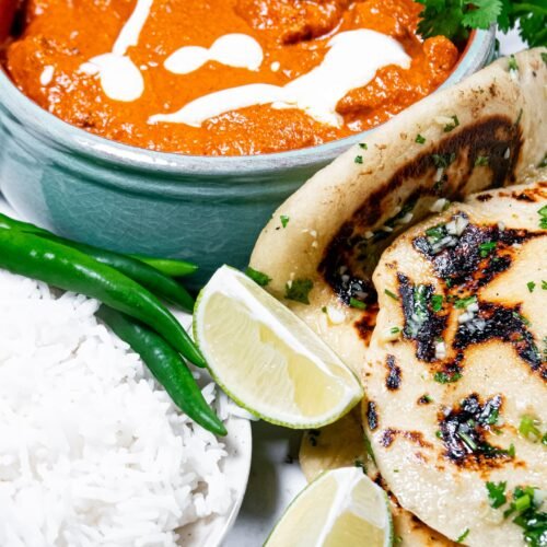 Creamy Butter Chicken served with garlic naan, basmati rice, green chilies, and lime wedges. A rich, restaurant-style Indian dish.