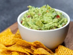 Fresh homemade guacamole with avocado, lime, tomato, and cilantro, served with tortilla chips.