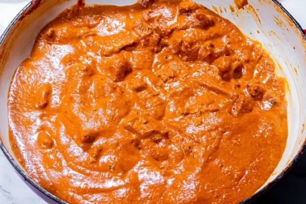 Creamy Butter Chicken simmering in a rich, spiced tomato sauce after adding baked chicken and heavy cream.
