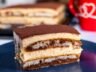 A slice of authentic Italian tiramisu with layers of creamy mascarpone, espresso-soaked ladyfingers, and a dusting of cocoa powder, served on a dark plate.