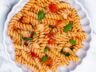 A plate of Classic Tomato Garlic Pasta with fresh basil, sautéed garlic, and a light tomato sauce, served in a white dish.
