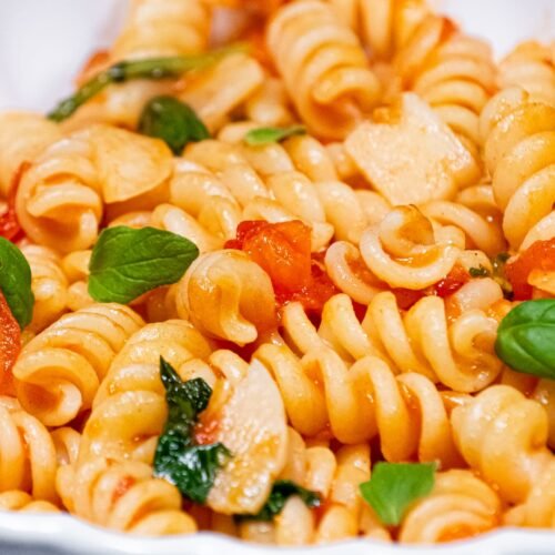 Close-up of Classic Tomato Garlic Pasta with fresh basil, golden garlic slices, and juicy tomatoes in a light olive oil sauce.